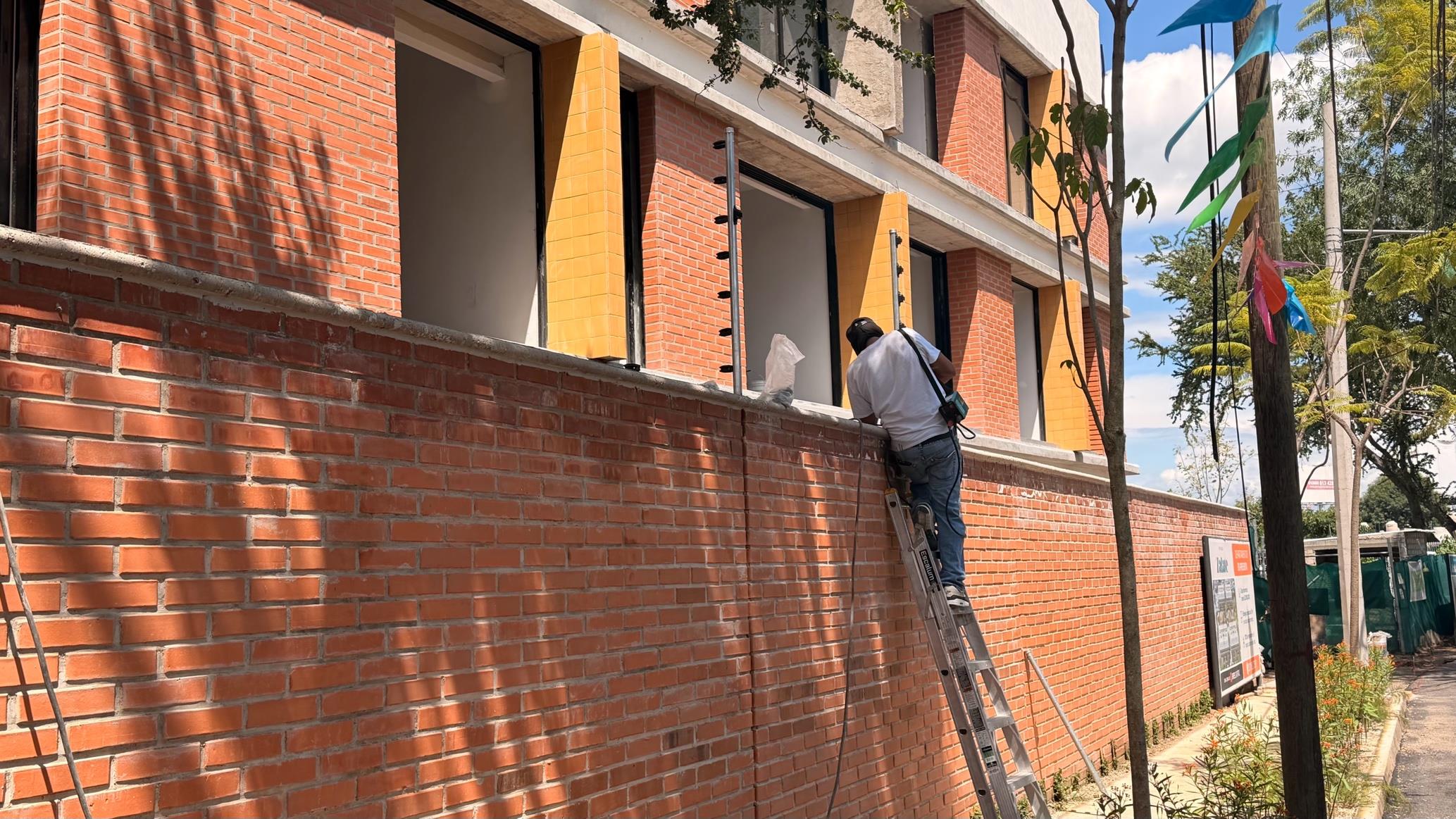 Fachada de ladrillo de la Torre 1 desde la banqueta, con la jardinería ya sembrada